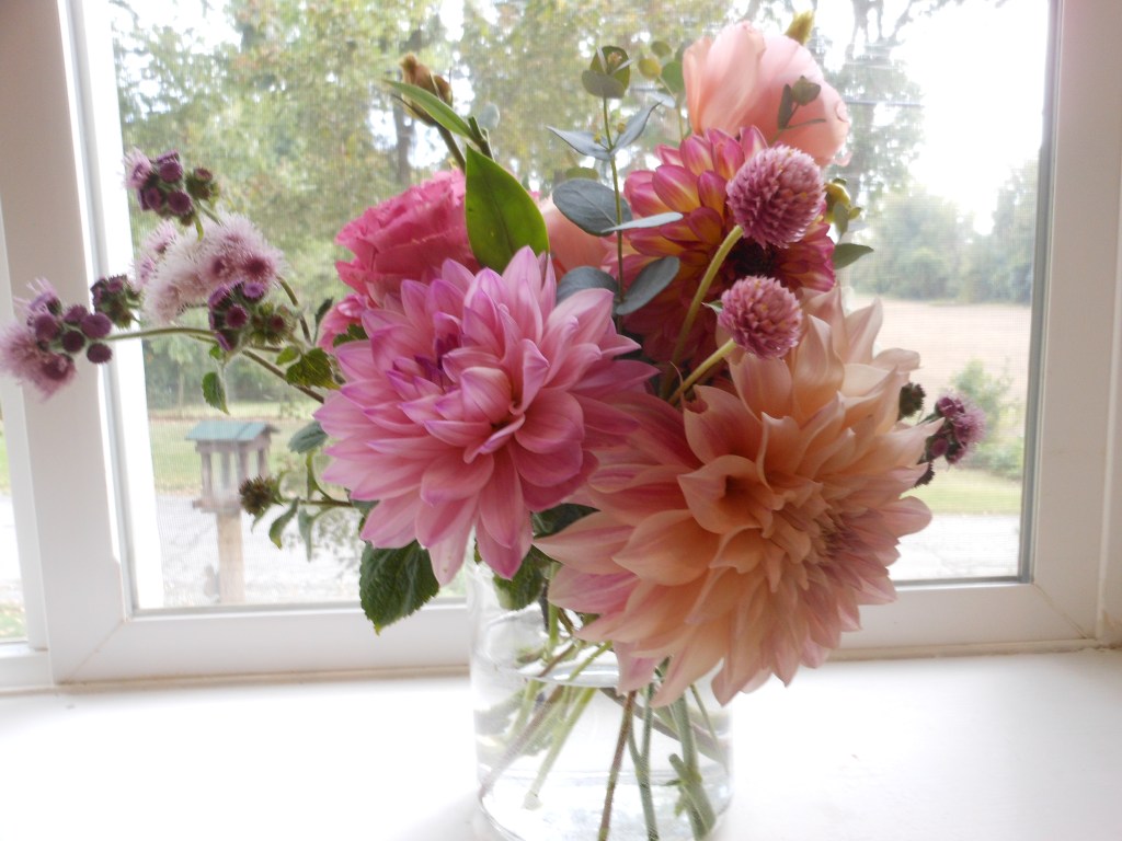 An assortment of pink, white and blush flowers in a medium-small vase.