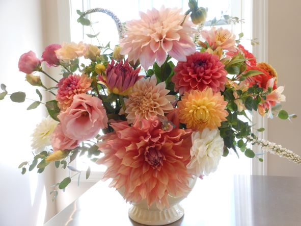 A custom floral design from Day florist Hudson Michigan sitting in front of the window. Featuring pink dahlias and greenery.